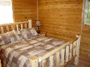 Bedroom on main level. Features log queen size bed.